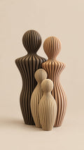 Three ribbed printed figurines shaped like stylized human figures, shown in dark brown, light brown, and beige tones against a warm beige background.